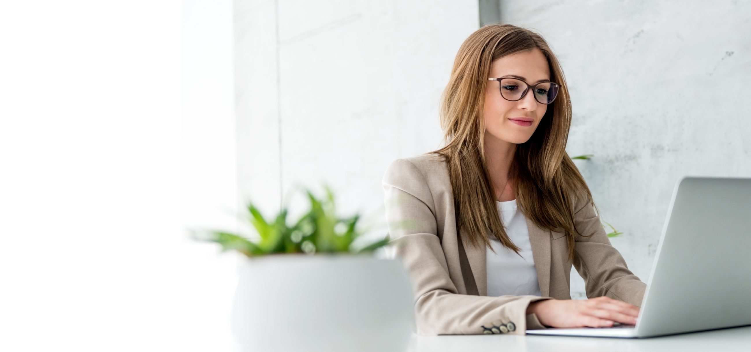 Young woman sitting at her desk working on a laptop
